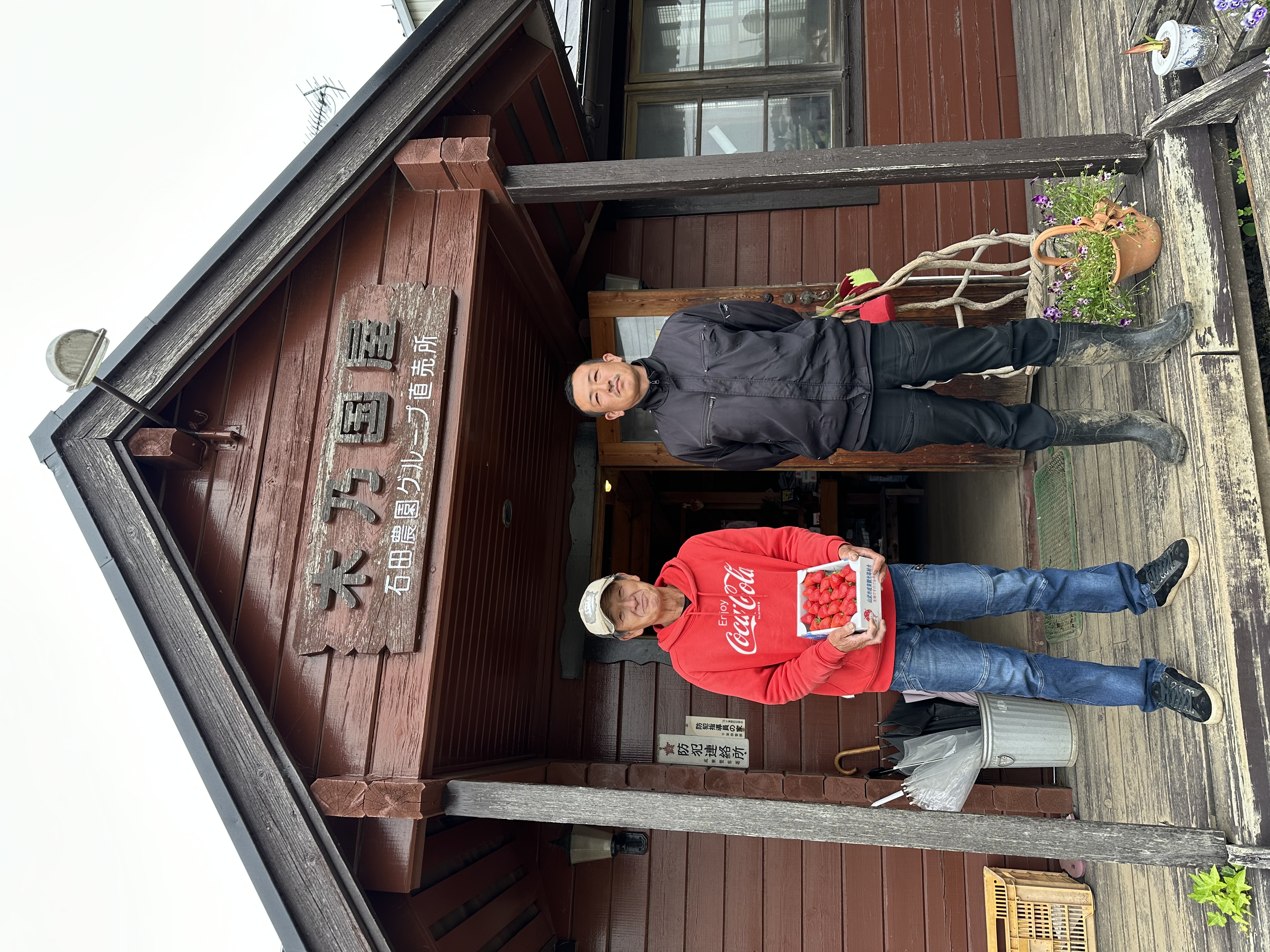 石田農園 親子二代の園主が直売所ログハウス「木乃国屋」の前で完熟いちごを持つ写真